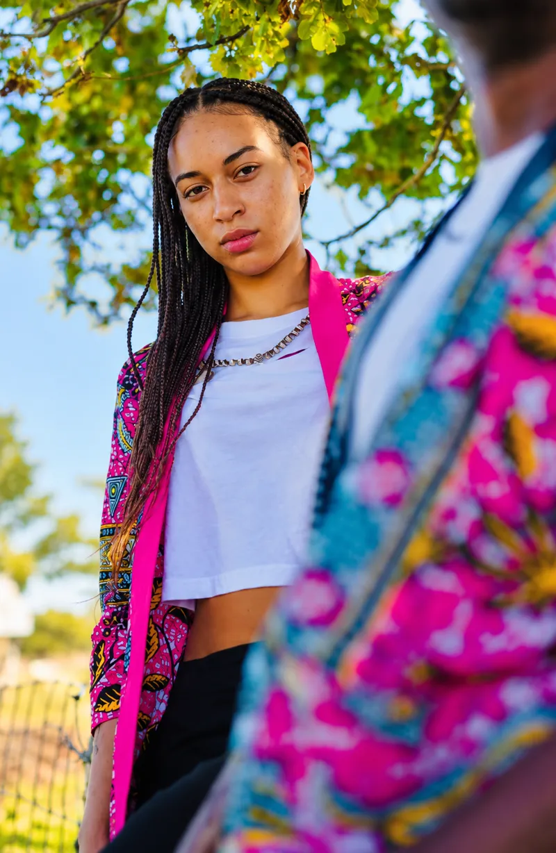 Customer in a pink floral print kimono over a white top, photographed under a tree