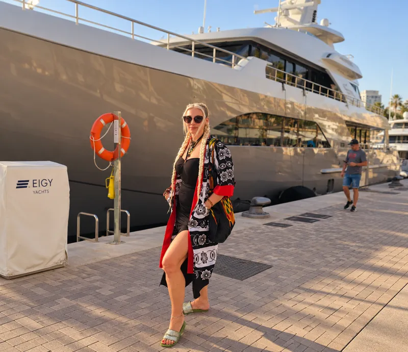 Customer in a black, white and red print kimono dress beside a marina full of yachts