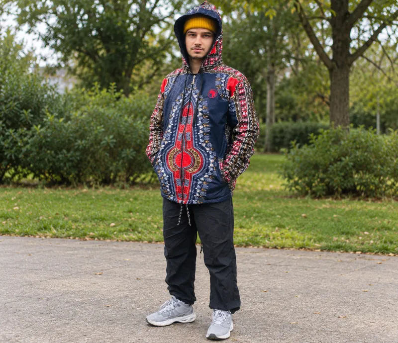 Customer in a navy and red print hooded jacket and yellow beanie on a park path